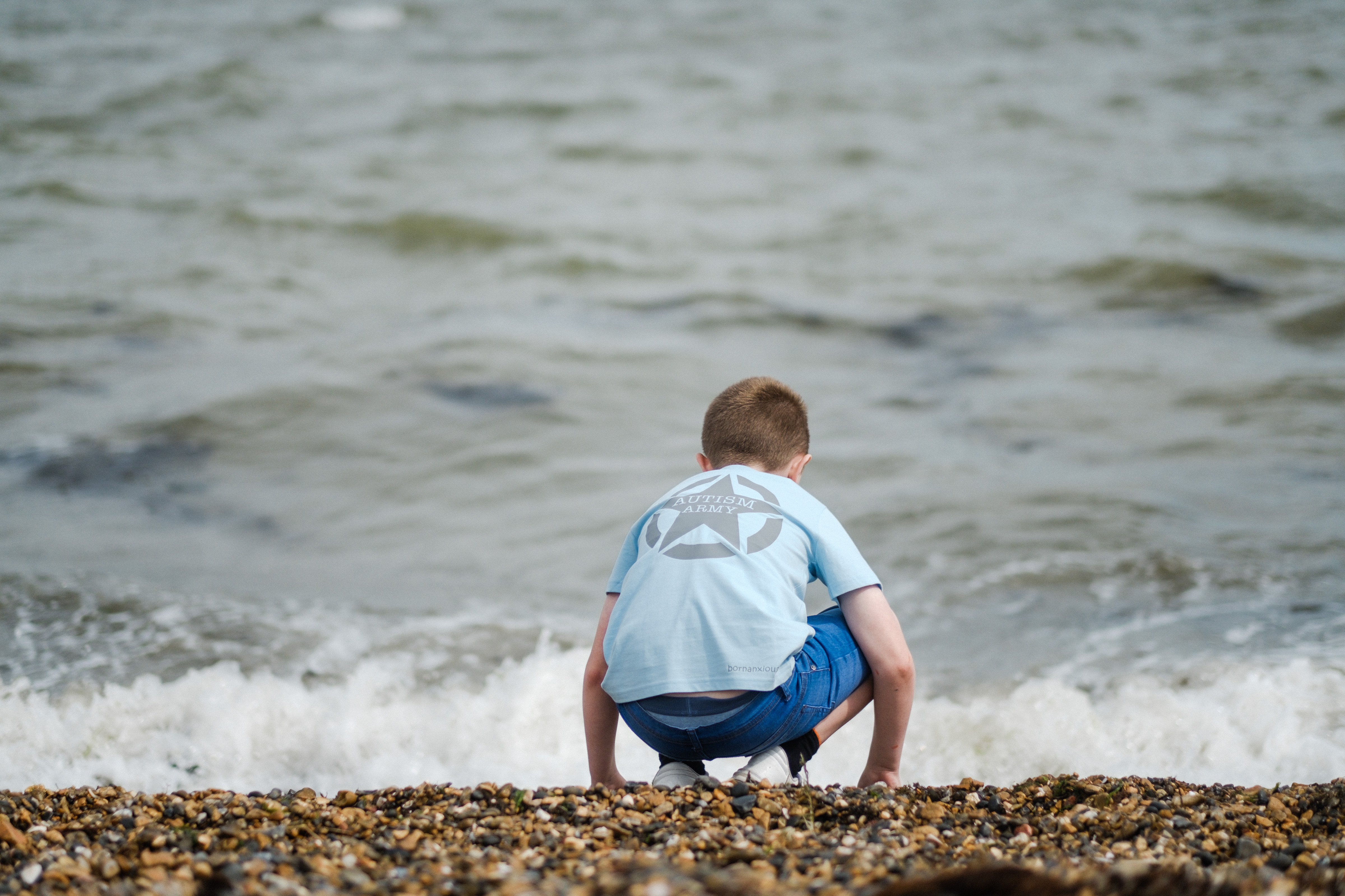 Oscar wears a light blue t shirt playing on the beach